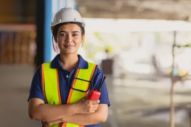 Woman in hard hat, outside with radio