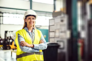 Woman in PPE smiling with arms crossed