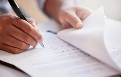Close up of hand holding pen, poised to write or sign a document