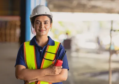 Woman in hard hat, outside with radio