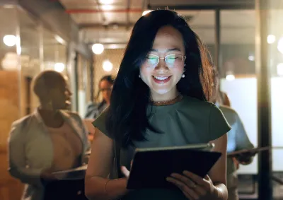 Woman working on ipad walking infront of colleagues