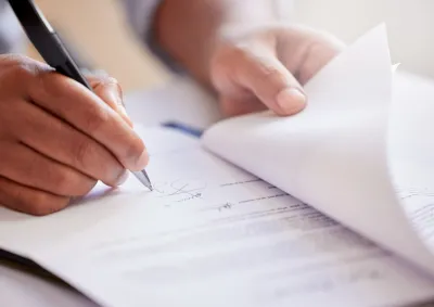 Close up of hand holding pen, poised to write or sign a document